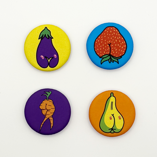 Four colorful button-style magnets with vegetable designs on a white background